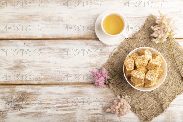 Traditional turkish delight (rahat lokum) in white ceramic plate with cup of green tea on a white