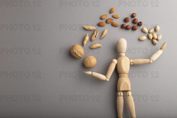 Wooden mannequin juggling nuts on gray pastel background. close up, isolated, delivery concept,