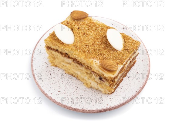 Honey cake with milk cream, caramel, almonds isolated on a white background. Side view, close up