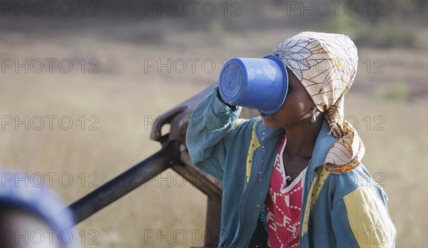 Young woman, girl drinking water from a plastic cup in Maraban Dare community in Plateau state,