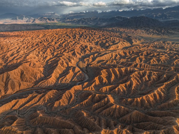 Landscape of eroded hills, badlands at sunset, mountain peaks of the Tian Shan Mountains in the