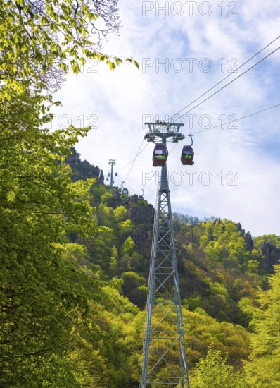 Cable car or gondola lift over a wooded mountain slope with cabins or gondolas and cable car