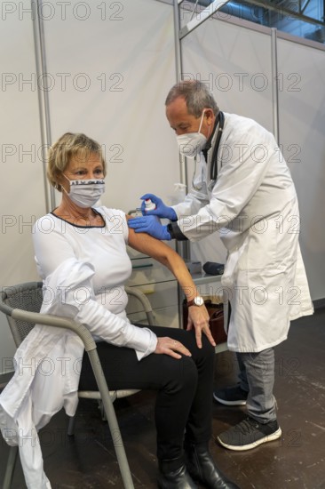 Vaccinator administers a vaccination, during the test run in the vaccination centre for corona
