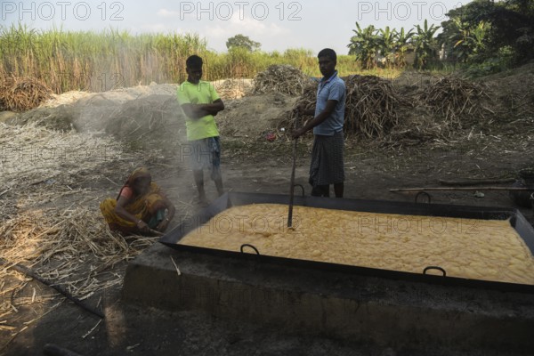 Workers boiling sugarcane juice as they are making Gur (jaggery) in a village on December 10, 2021