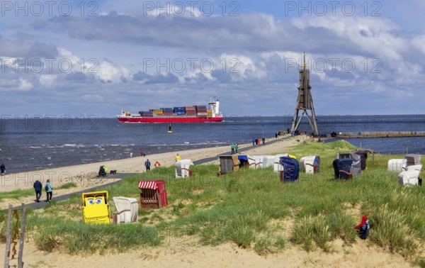 Beach promenade with landmark Kugelbake and container ship in the district of Döse, North Sea spa