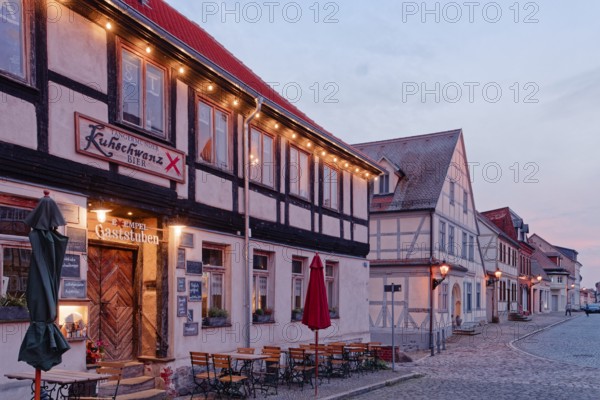 A festively illuminated restaurant in the evening and half-timbered houses in the cobbled