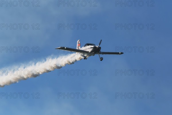 Stunt aerobatic plane performing stunts in blue sky with smoke trail. Concept of speed, difficulty,