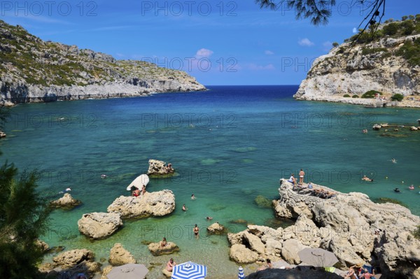 An idyllic bay with crystal-clear water, surrounded by rocks under a bright blue sky, Anthony Quinn