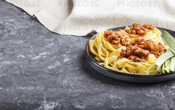 Tagliatelle bolognese pasta with minced meat on a black concrete background. side view, close up,