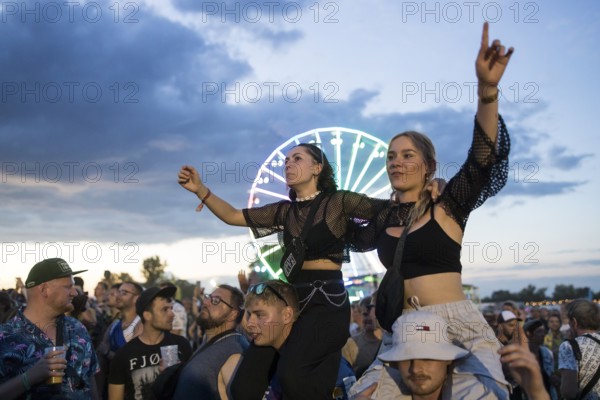Festival visitors celebrate on shoulders during Ski Aggu's performance in front of the Ferris wheel