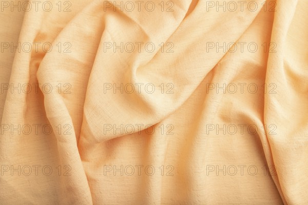 Fragment of orange linen tissue. Top view, natural textile background and texture. wave concept,