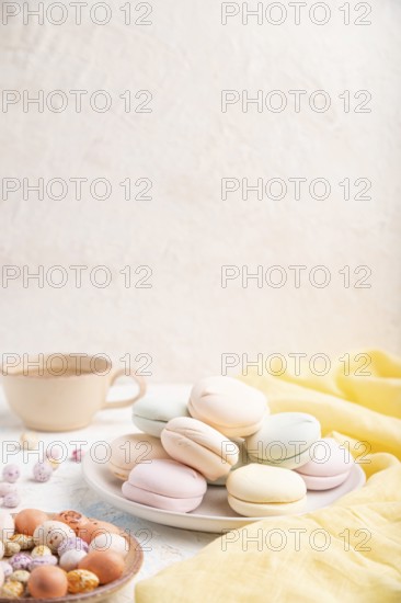 Colored zephyr or marshmallow with cup of coffee and dragees on white concrete background and