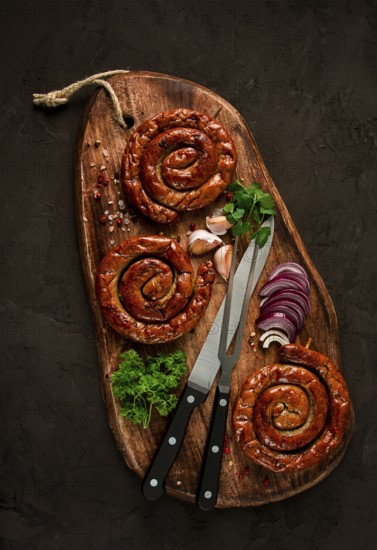 Fried spiral sausages, on a wooden board, top view, with spices, no people