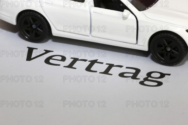Symbolic image of car insurance: model car with contract documents
