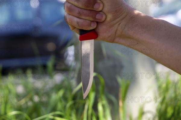 Symbolic image of a knife attack: close-up of a knife in a man's hand