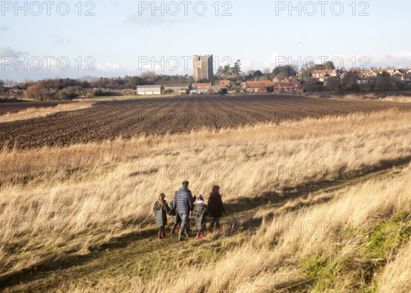 Family walking by the village and castle looking across fields, Orford, Suffolk, England, United