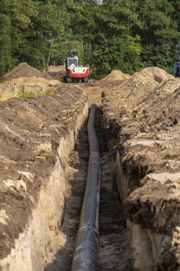 Laying of district heating pipes, next to a field, with maize, the district heating comes from a