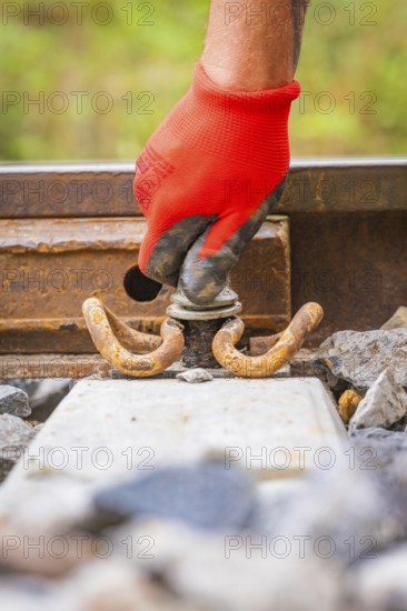 Close-up of a red-gloved hand working on a tool on rails, track construction, Hermann Hessebahn,