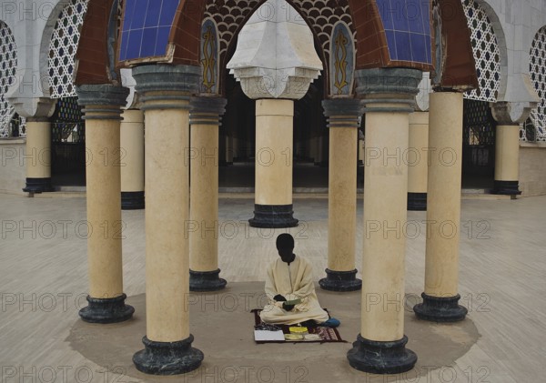 A muslim religious student is reading a book in the Great Mosque at Touba Senegal