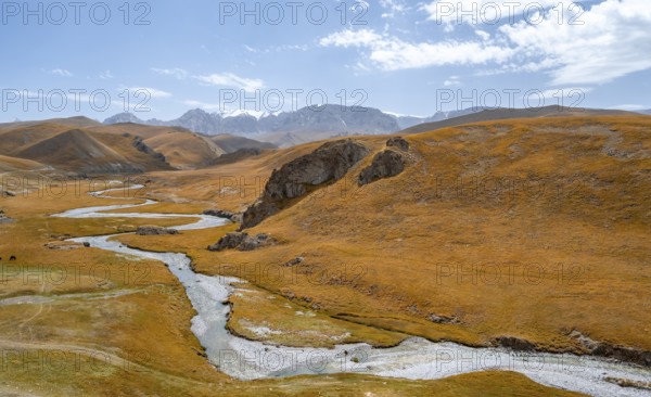 River Kol Suu winds through a mountain valley with hills of yellow grass, Naryn Province,