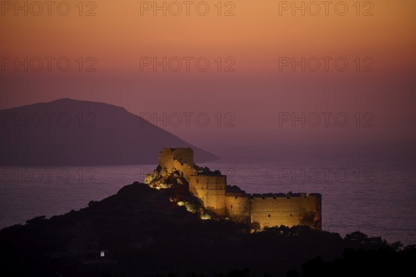 Illuminated castle ruins at dusk with a view of the sea and the surrounding mountains, Kritinia