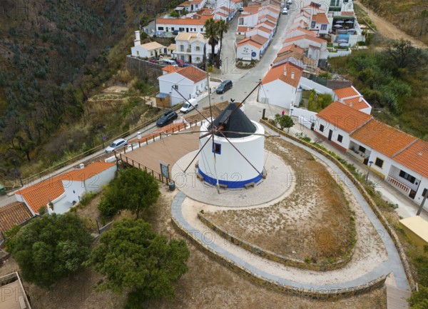 Aerial view of a village with a central windmill surrounded by houses with orange-coloured roofs,