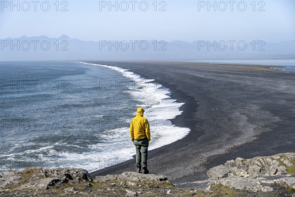 Tourist looking over long black sand beach, Reynisfjara Beach, South Iceland, Iceland, Europe
