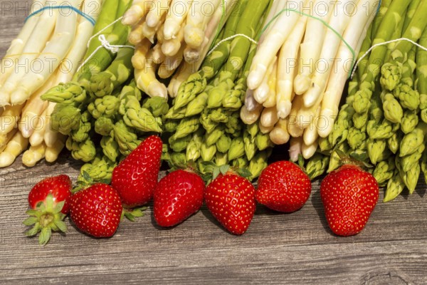 Green asparagus, white asparagus and fresh strawberries decorated on a rustic wooden table