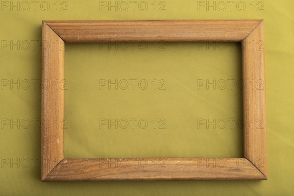 Wooden frame on smooth green olive silk tissue. Top view, flat lay, natural textile background and
