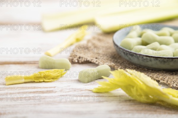 Jelly celery candies on white wooden background and linen textile. close up, side view, selective