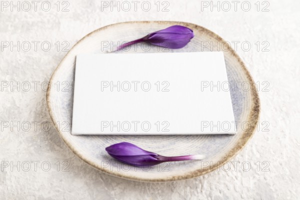 White paper invitation card, mockup with crocus flowers on ceramic plate and gray concrete