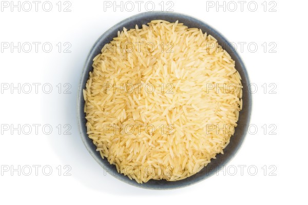 Blue ceramic bowl with raw golden rice isolated on white background. Top view, close up