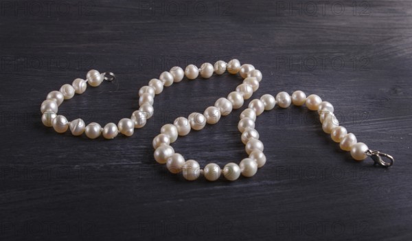 Caramel colored pearl beads on a black background. top view, close up
