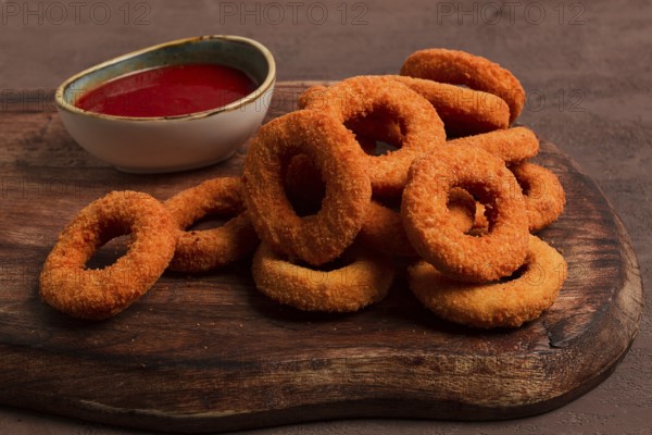 Crispy chicken rings, fried, on a wooden board, close-up