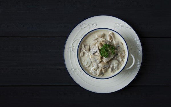 Cream sauce with mushrooms, top view, on a dark gray wooden table, horizontal, no people