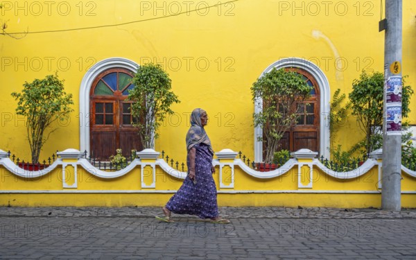 Street scene with Indian woman in front of yellow house, Fort Kochi, Cochin, Kerala, India, Asia