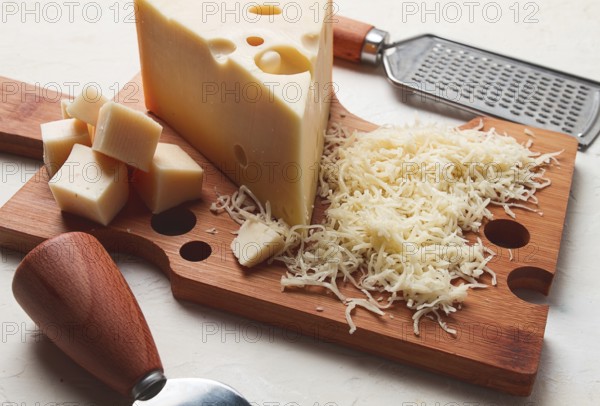 Grated cheese, Maasdam, on a cutting board, grater and cheese knife, close-up, no people