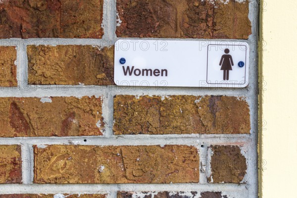 Sign on brick wall at entrance to Women's restroom