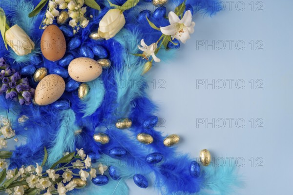A spring-like Easter egg decoration with blue feathers and white flowers on a light blue background