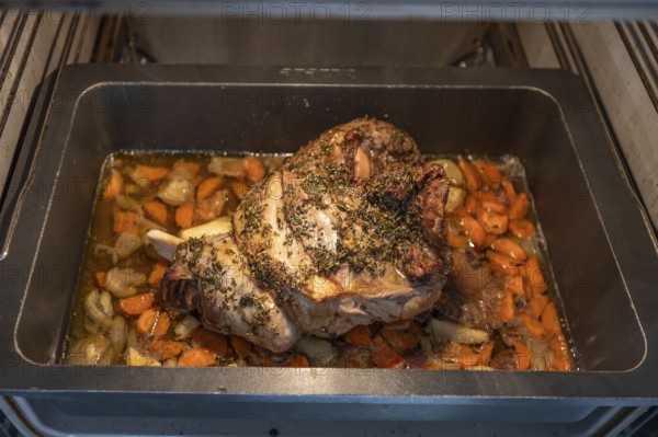 Freshly roasted roast lamb with herbs and vegetables in a casserole in the oven, Bavaria, Germany,