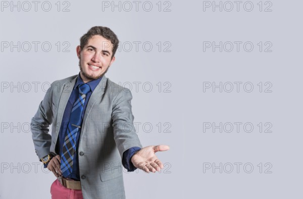Man extending his hand inviting, man in suit welcoming, man looking at camera presenting a product,