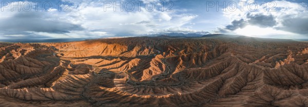 Panorama, landscape of eroded hills at Lake Issyk Kul, badlands at sunset, mountain peaks of the