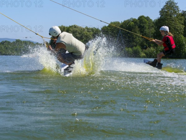 Children go wakeboarding together on the lake, water sports, water skiing and wake park