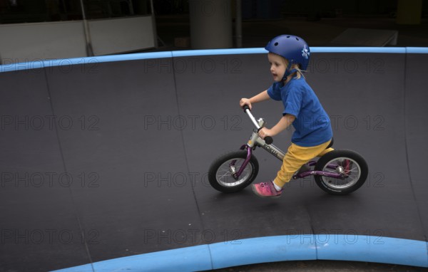 Little girl, 3 years, blonde, helmet, helmet, riding on balance bike, bicycle, skating rink,