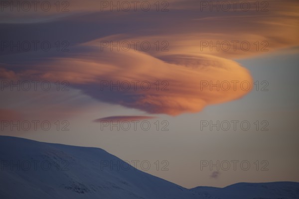 Lenticularis clouds at sunrise over mountains in winter