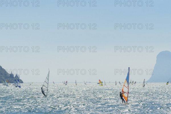 People windsurfing on a sunny day with clear blue skies and mountain backdrop, Lake garda, Torbole,
