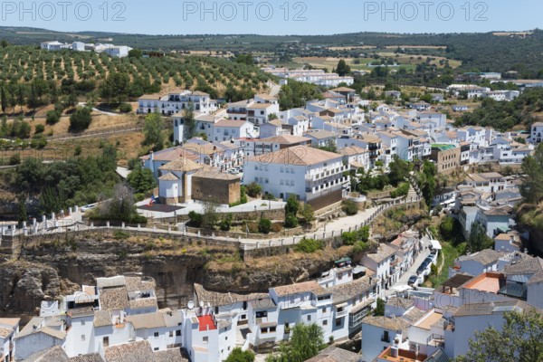 Panoramic view over a village with olive groves and white buildings on hillsides, cave dwellings,