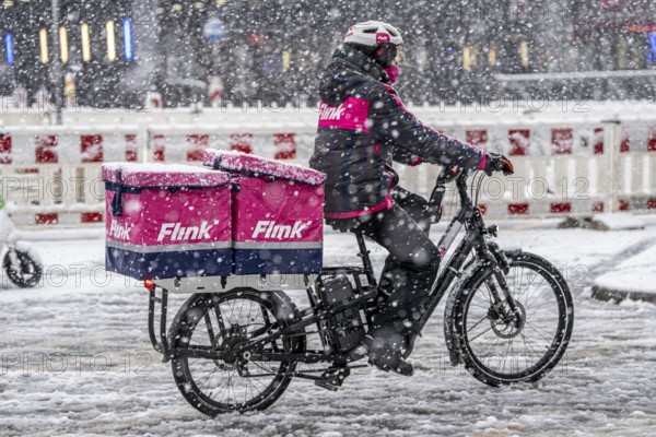 Winter weather, heavy snowfall, city centre traffic, courier of the delivery service Flink on