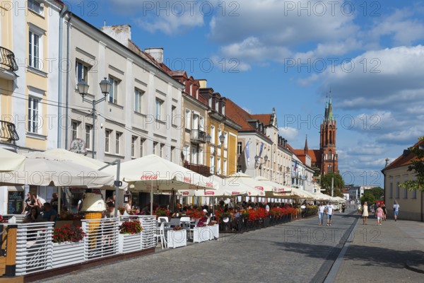 Lively street with historic houses and church tower in a summer atmosphere, Kosciuszko market