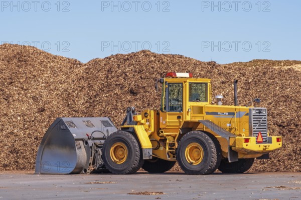Front loader with a large bucket on a loading area for wood chips